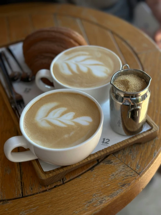 two cups of  cocoa sit on a table with silverware