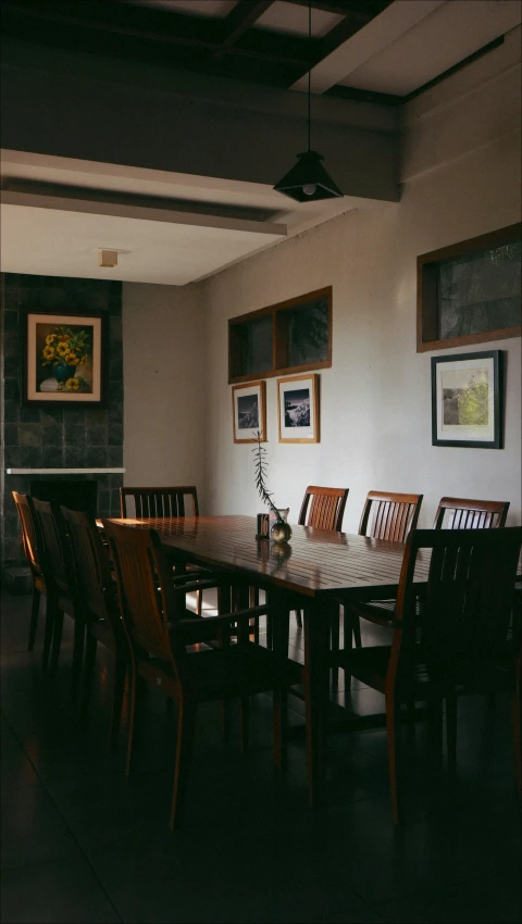 a dining table with six wooden chairs and two pictures on the wall