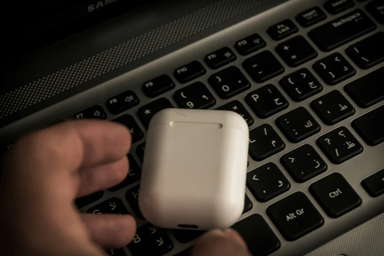 a man using a small plastic object on a computer keyboard