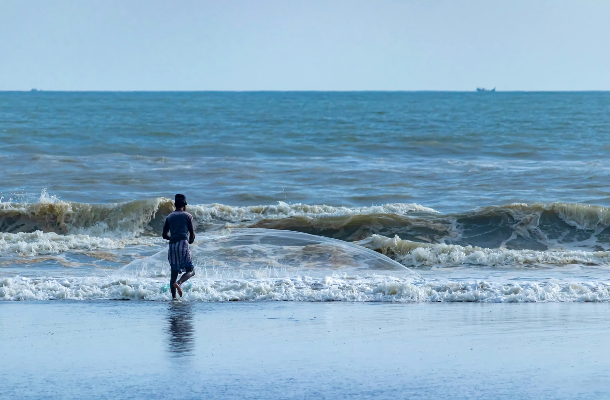 boy walking on the beach at the edge of water