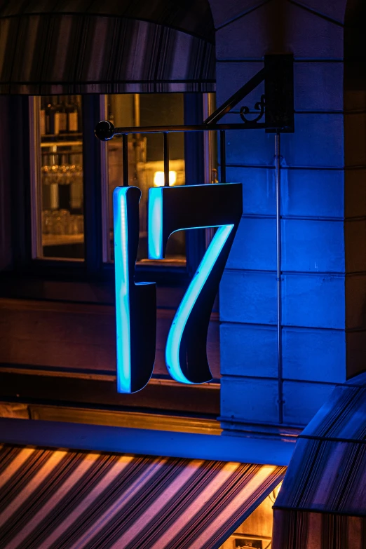 blue neon sign next to a wall on the outside