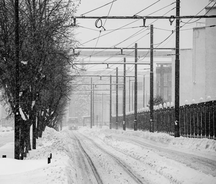 the view of a snowy street with power lines above it