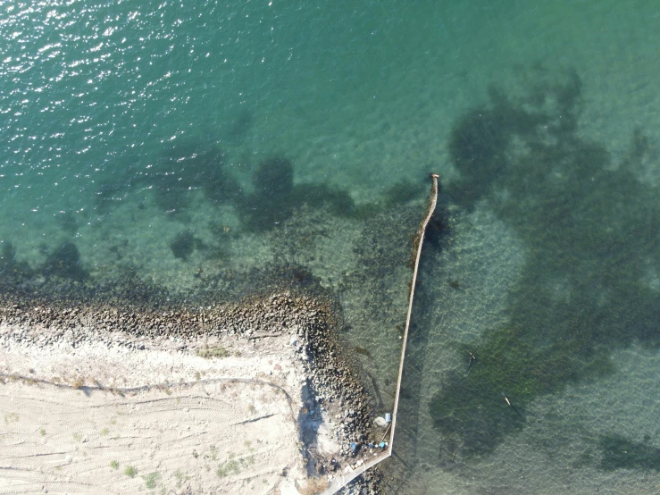 an aerial view of water and rocks on a shore