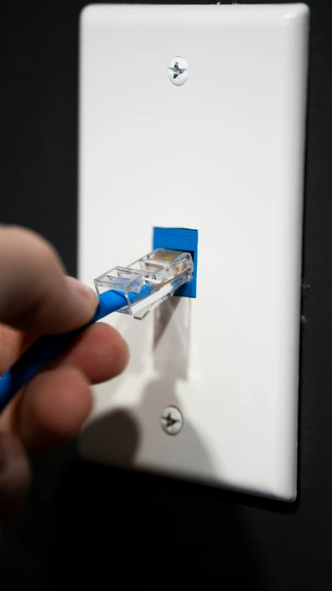 a person is fixing a light switch with a pair of blue scissors