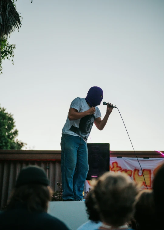 a man on stage with a microphone and wearing a hat