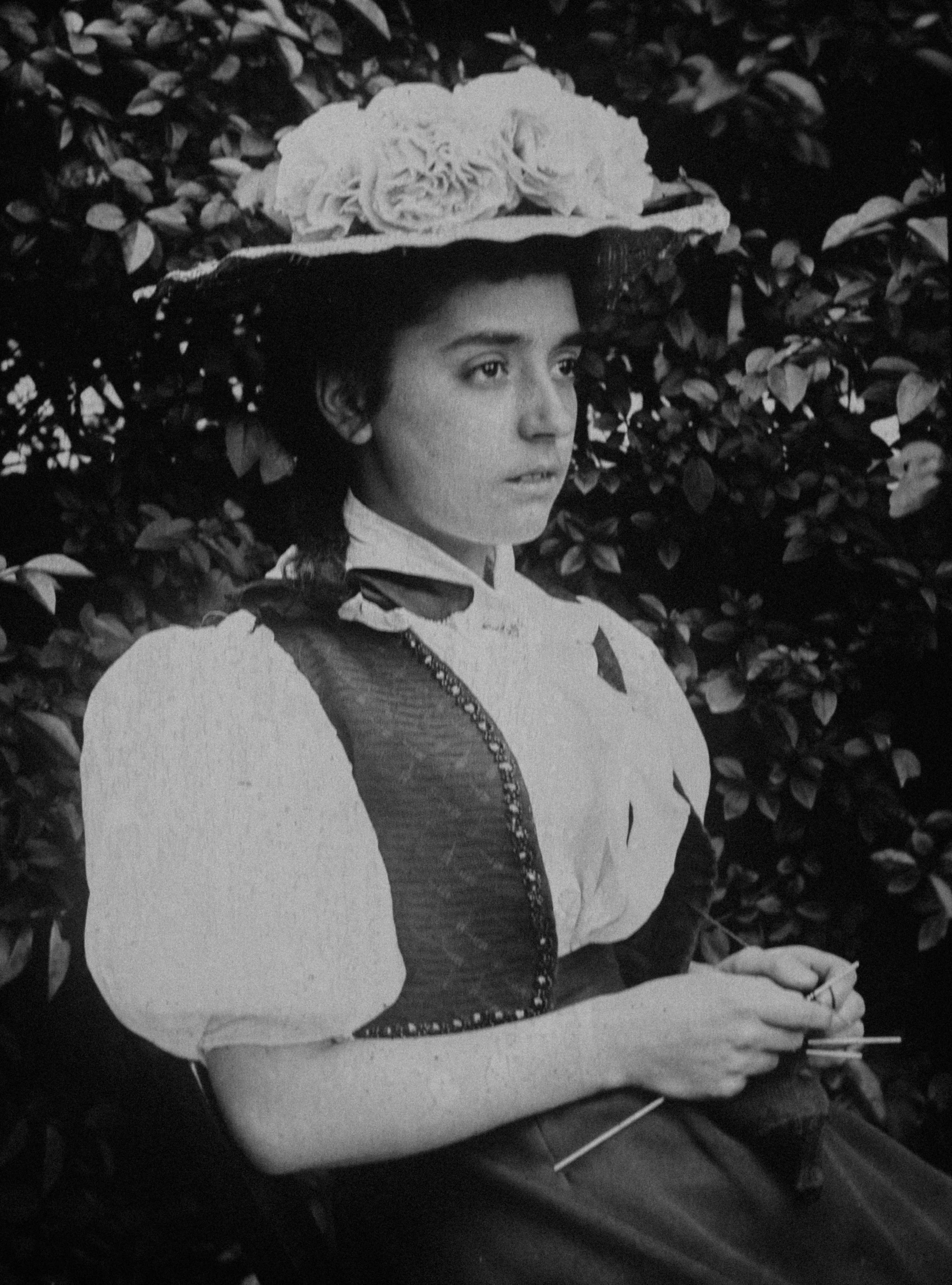 a young woman with a flower hat smoking a cigarette