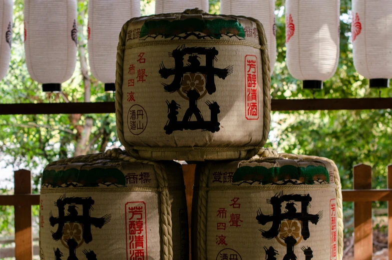 four large square asian barrels sitting on a fence