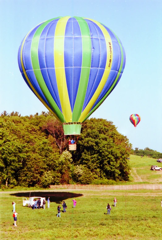 people gather in a field with many different types of balloons