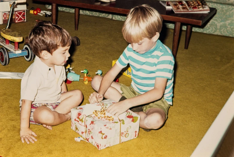 two s playing with a gift box on the floor