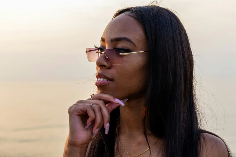 an african american woman wearing sunglasses, looking at the ocean