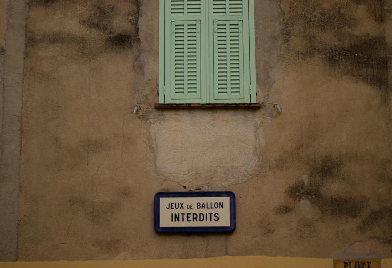 two green windows above a sign in front of a beige wall