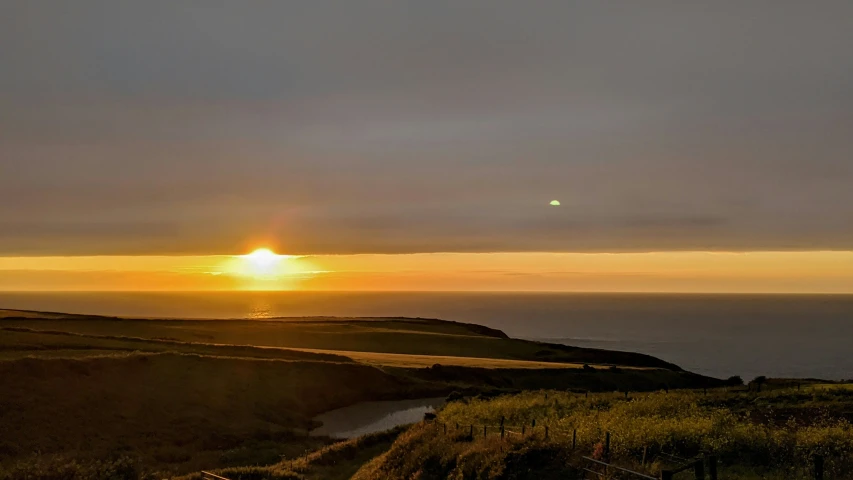 the sun is setting over a rocky beach