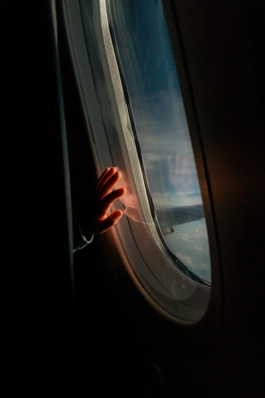 a hand is on a window that can be seen through the airplane