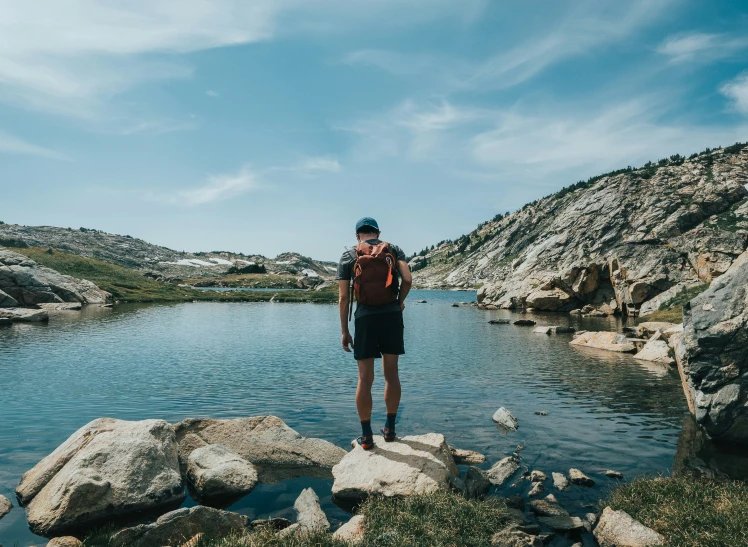 the man is standing on rocks by the water