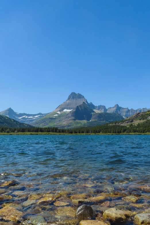 water with rocks in it and mountain peaks in the background