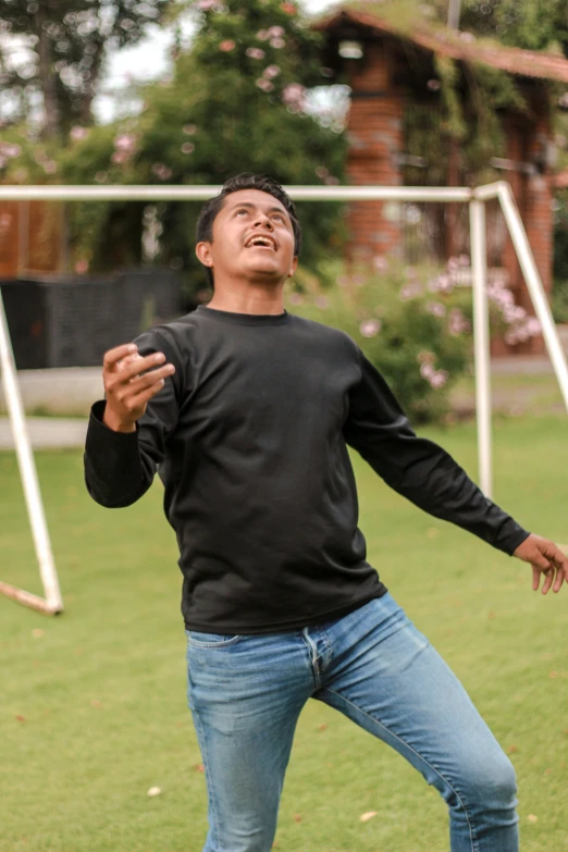 the man is outside in his black sweater catching a frisbee