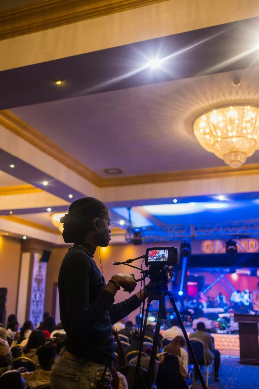 a man is standing on a stage and filming the audience