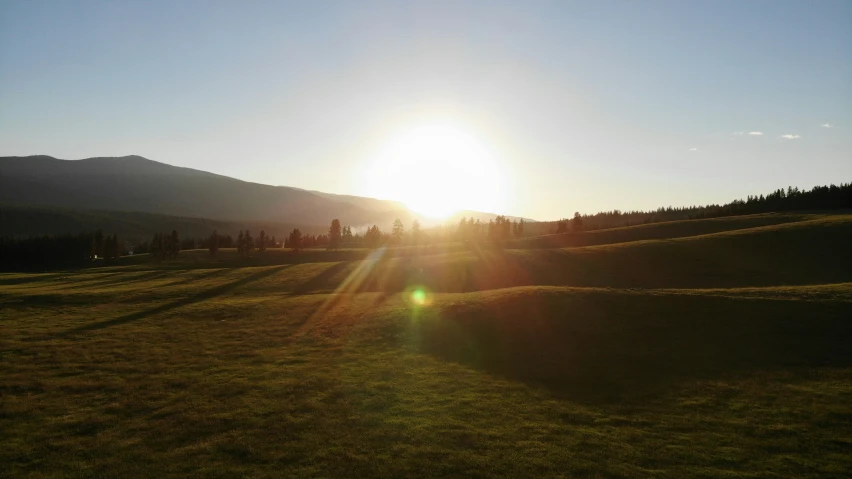 the sun is set on the hillside with mountains in the distance