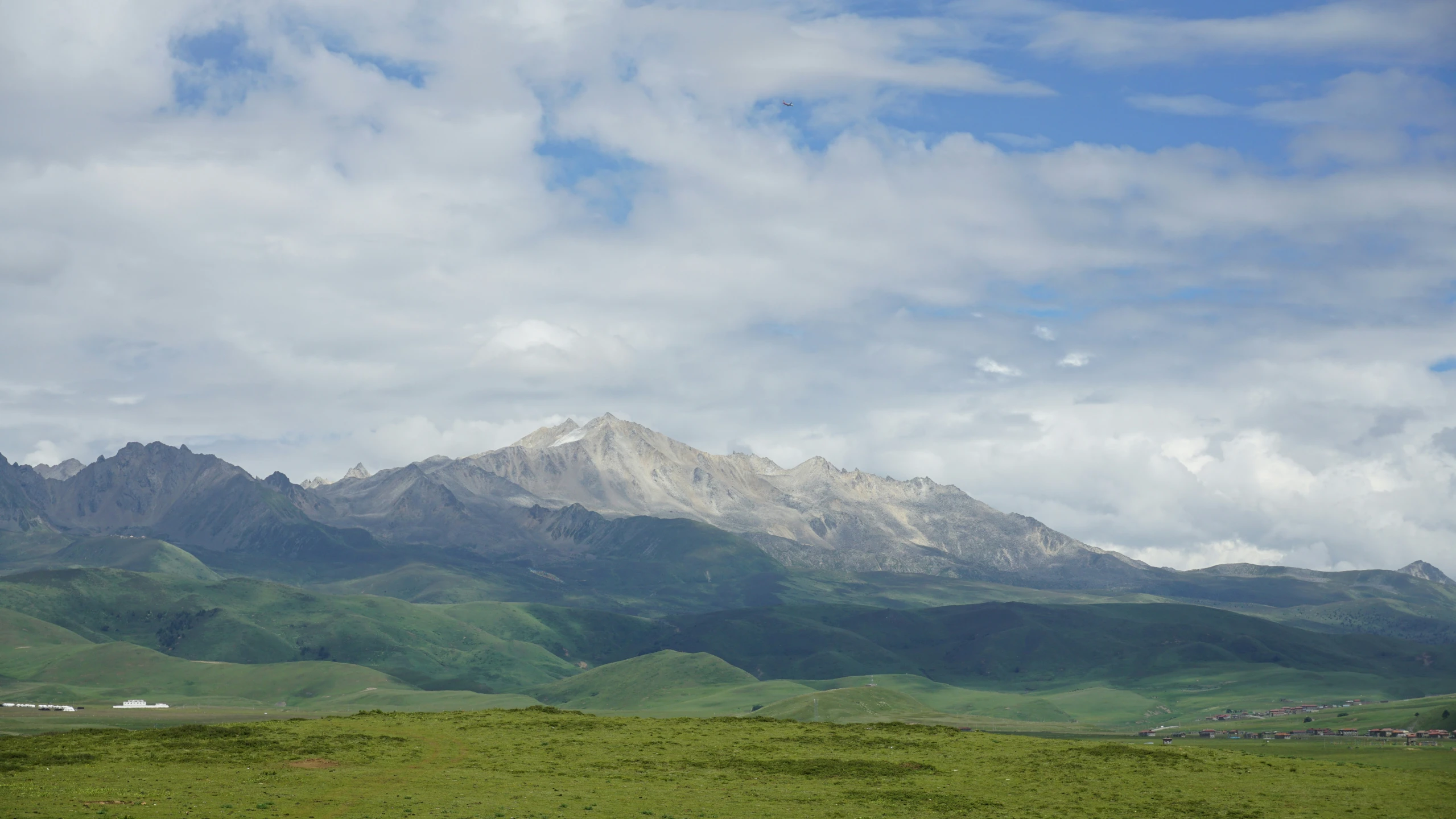 a mountain range covered with a lush green field