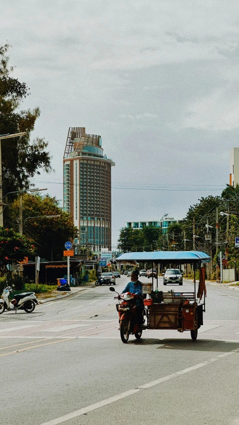 a man riding down the road next to a man on a small cart