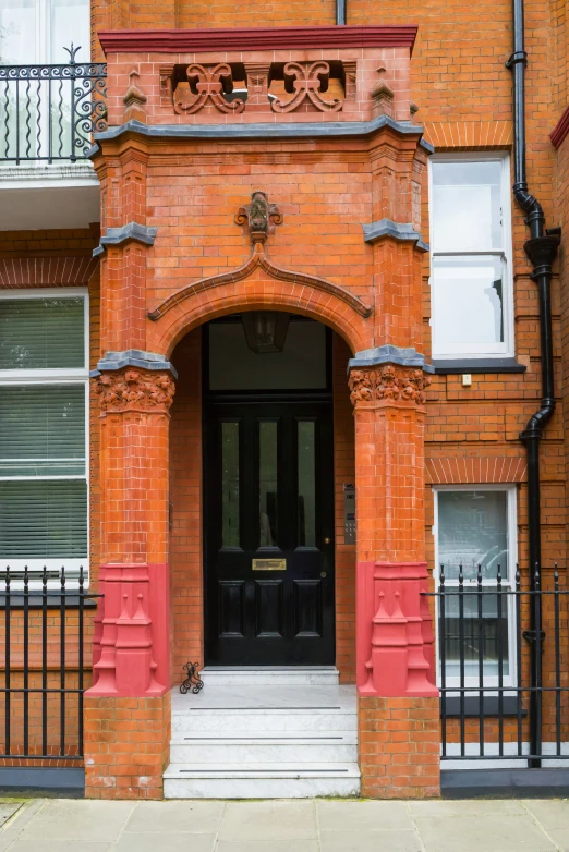 an ornate entrance to a brick building with iron fence