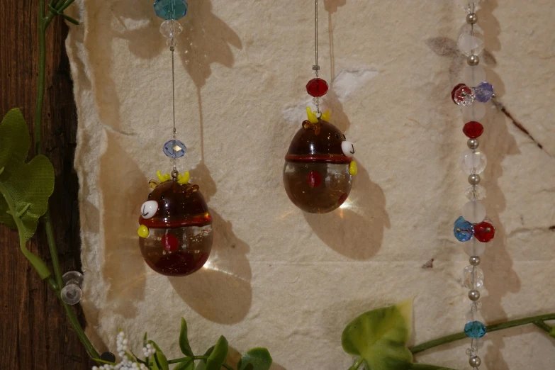 two pendants with beads and charms attached to a stone wall