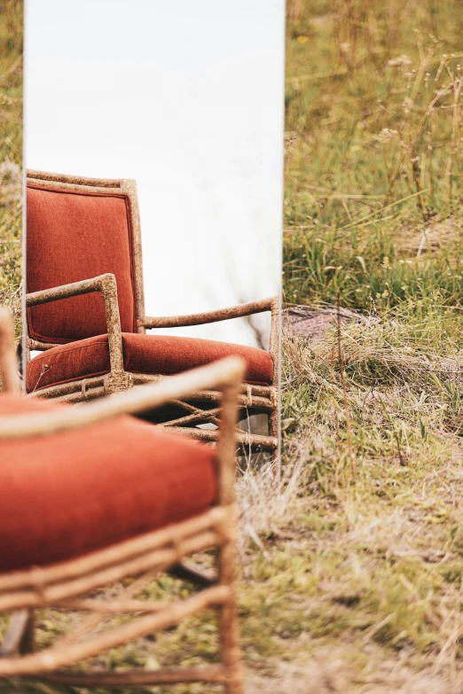 a chair and a mirror sitting in the grass