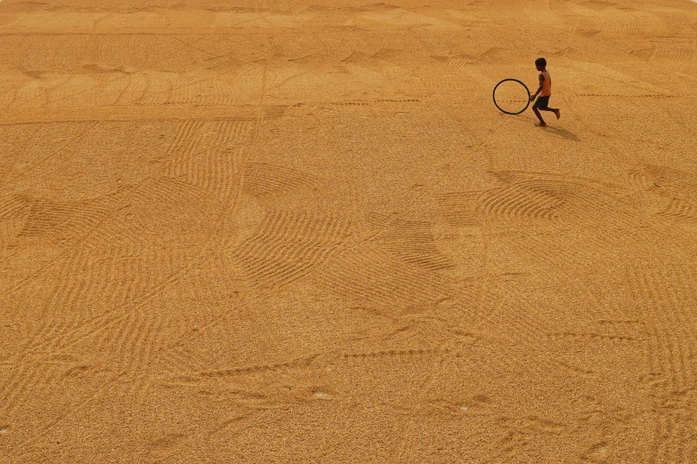 a man holding a tennis racket walking across the beach