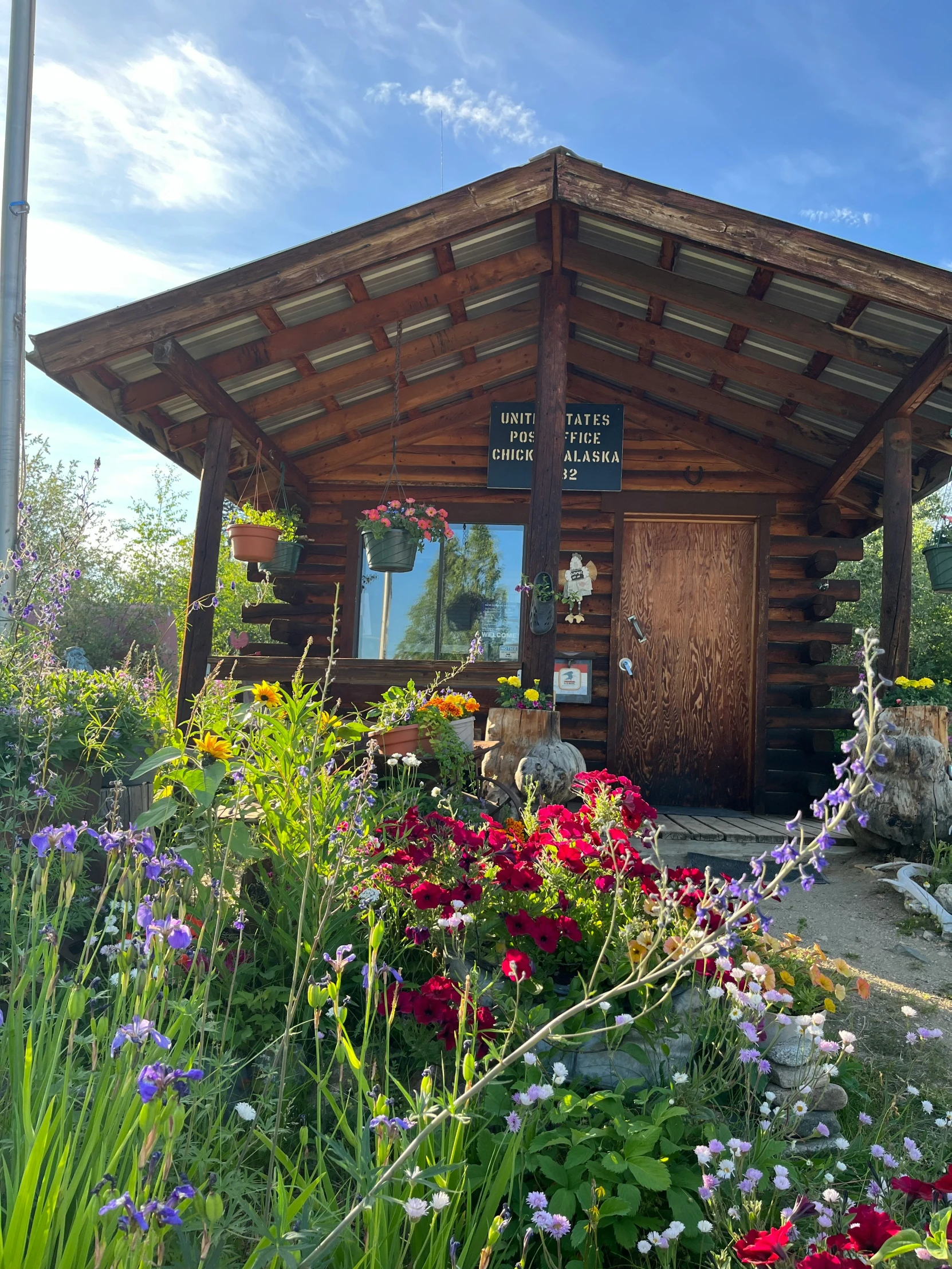 a cabin with flowers around the front in a garden