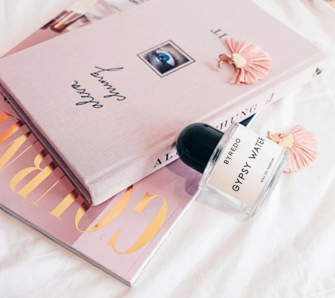 a pink book and some nail polish sitting on a bed