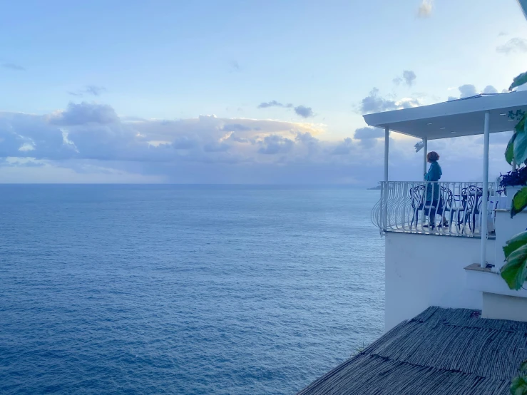 some people are standing on a balcony above the ocean