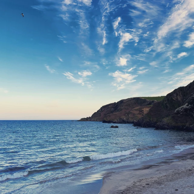 a small plane flying over the ocean and cliffs