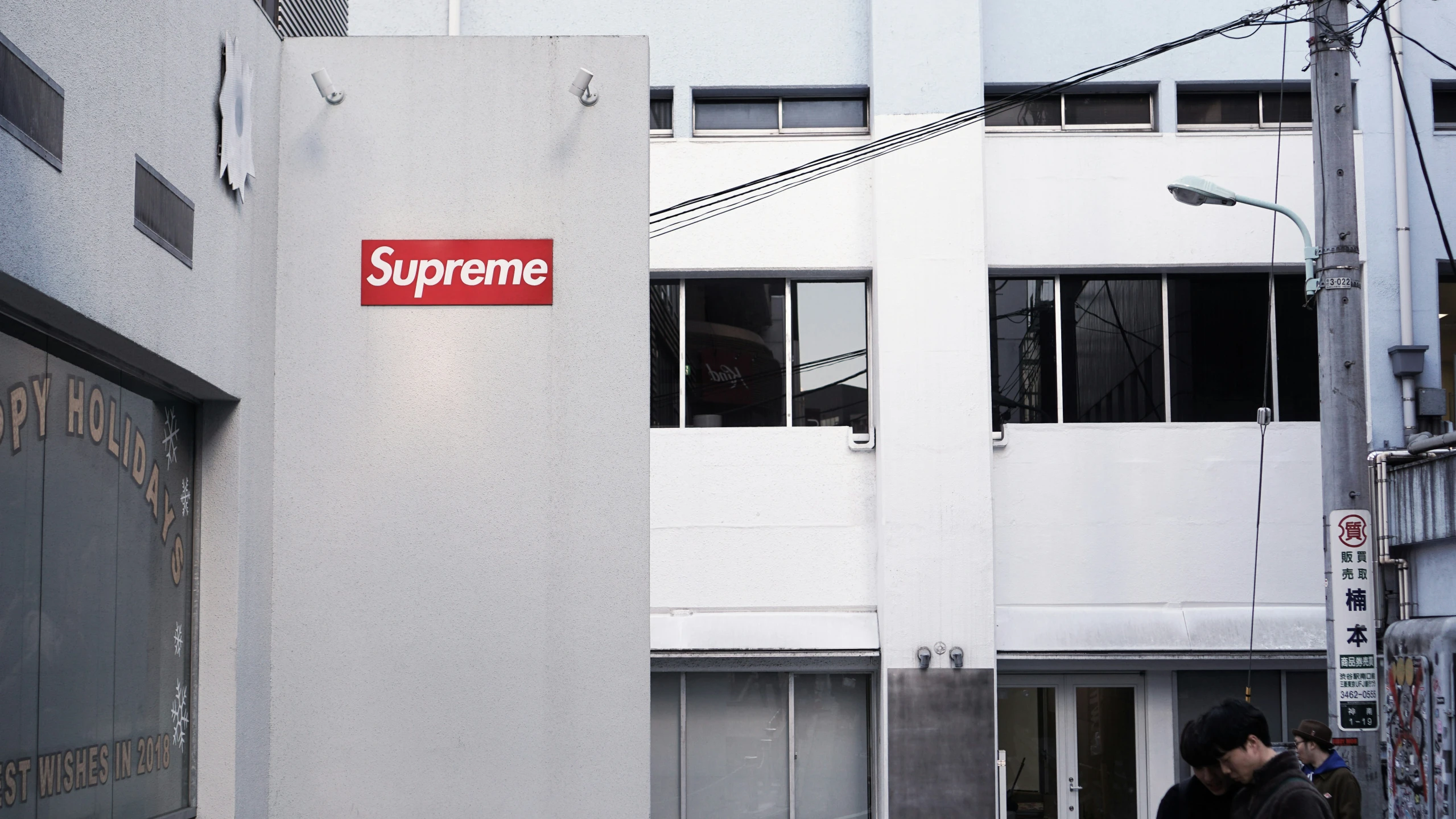 a red and white sign above an open door on a gray building