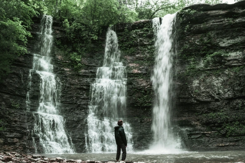 a man is looking at the water below the waterfall