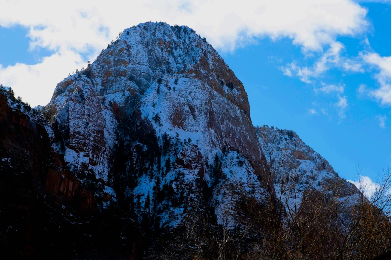 a tall mountain with snow on the top and trees below