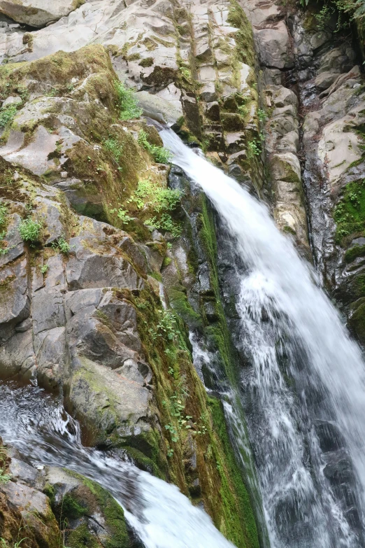 a very tall waterfall with rocks and some trees