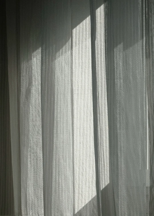 an open window curtain that is closed and partially covered by light