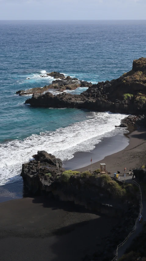 a beach area next to the ocean and some rocks