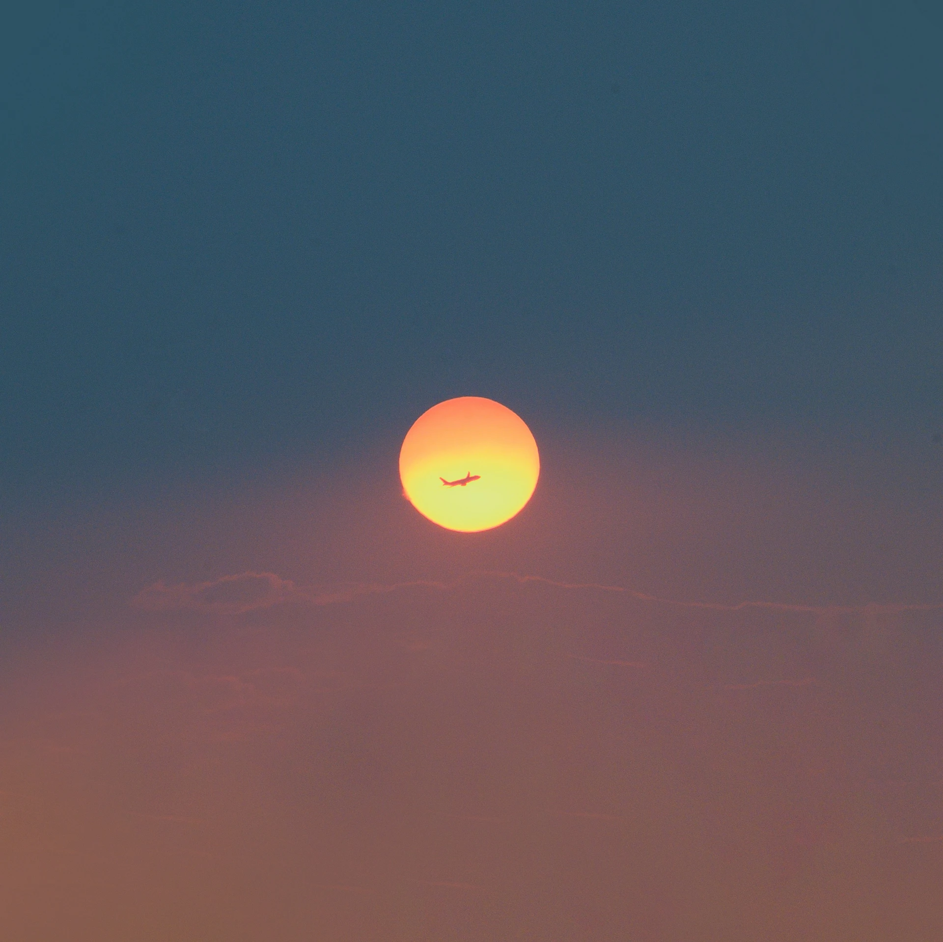 an airplane flying in front of the sun on a hazy day