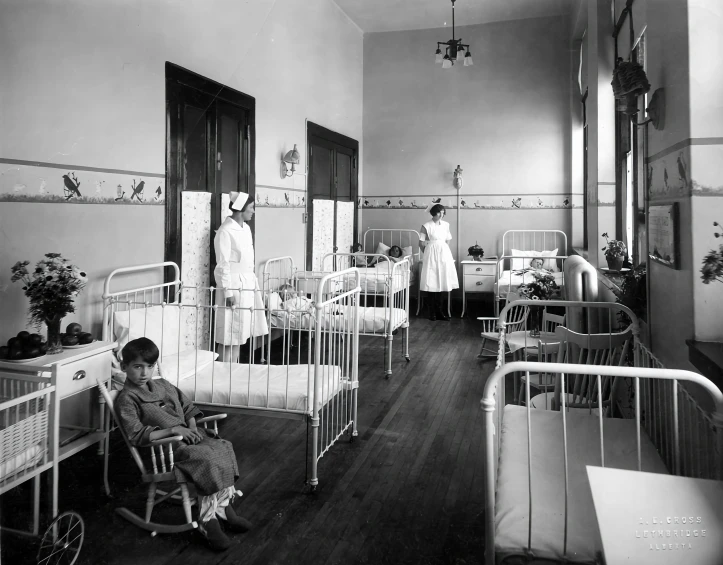 children in a hospital room with cribs and nurse