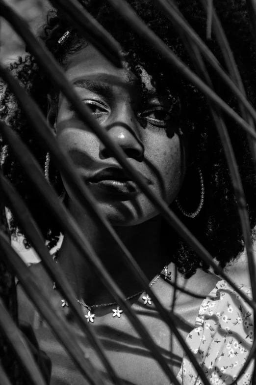 woman staring at the camera through palm leaves