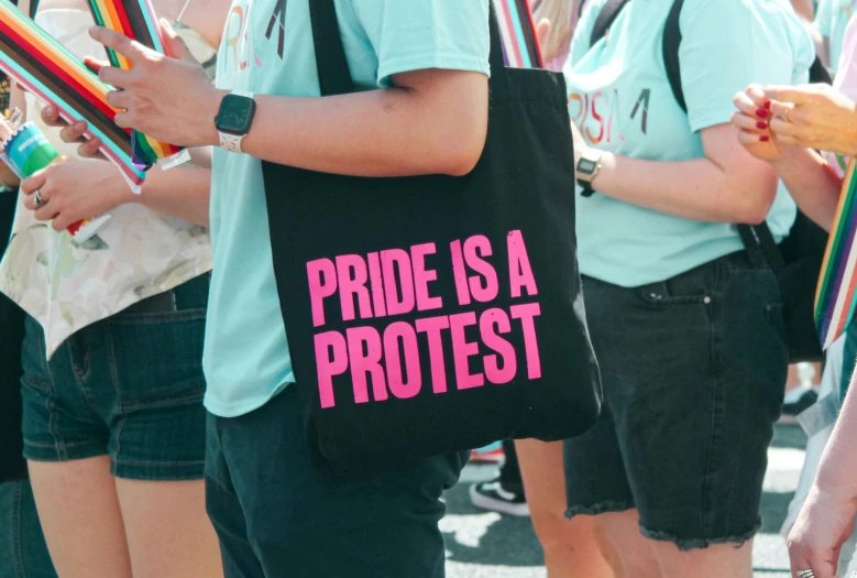 people carrying rainbow items and the words pride is a protest