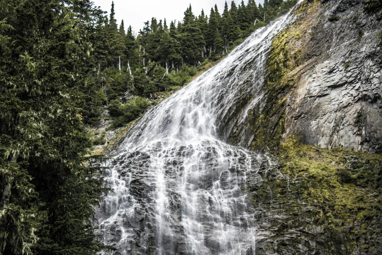 a tall waterfall falling down into the woods