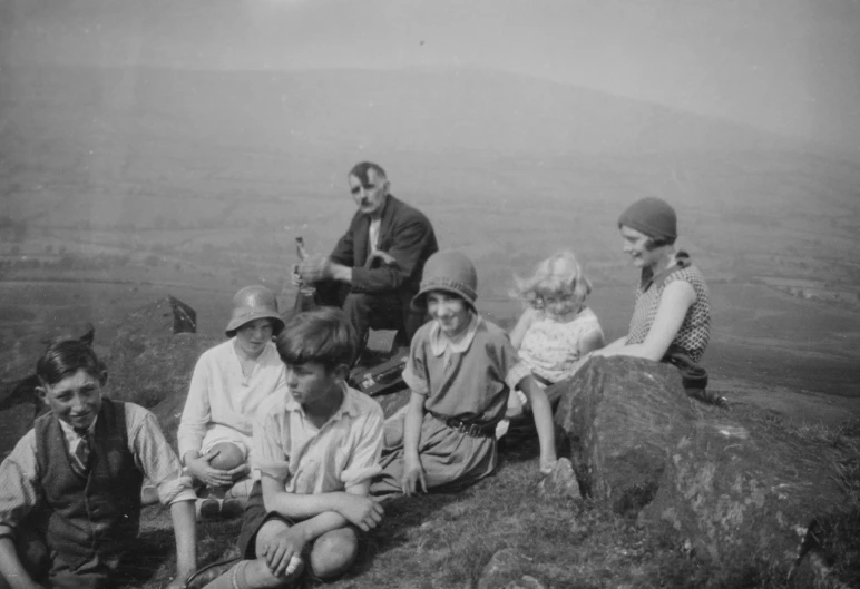 an old po shows several children and adults on a rocky hillside
