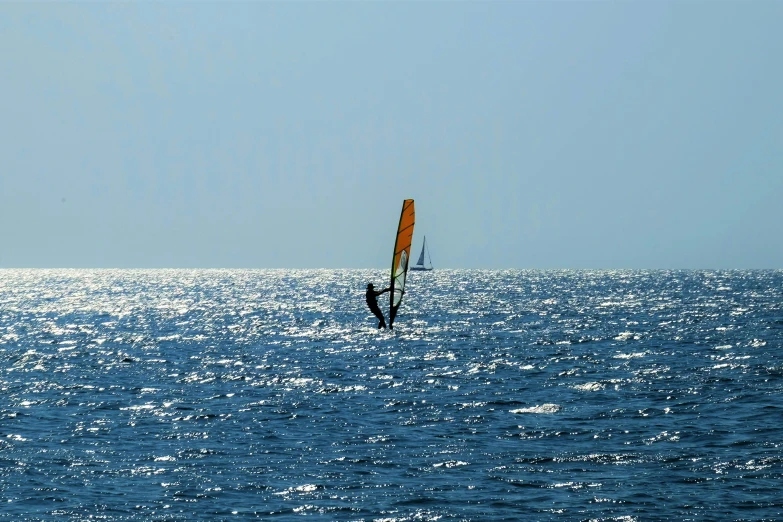 sail boarder gliding through blue water with sun shining