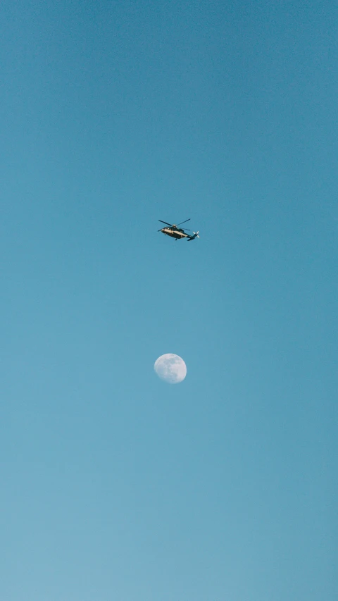 a helicopter flying through the sky over a moon