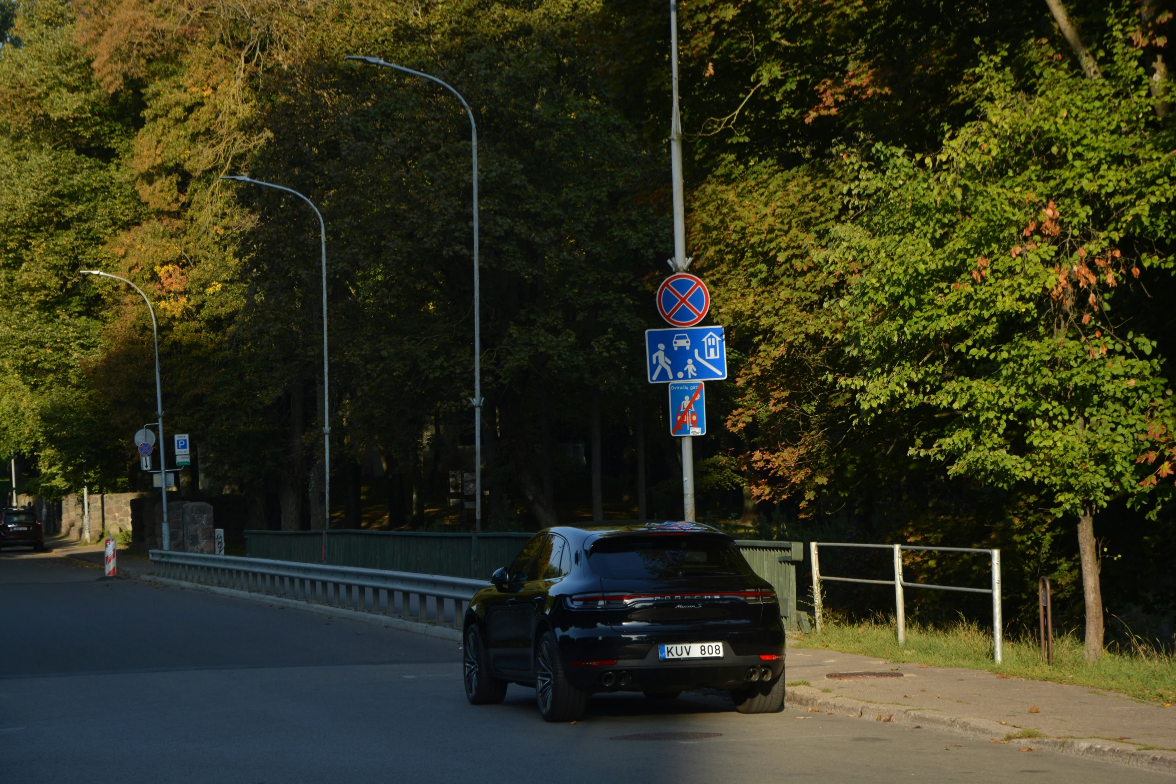 a black car is approaching a blue street sign