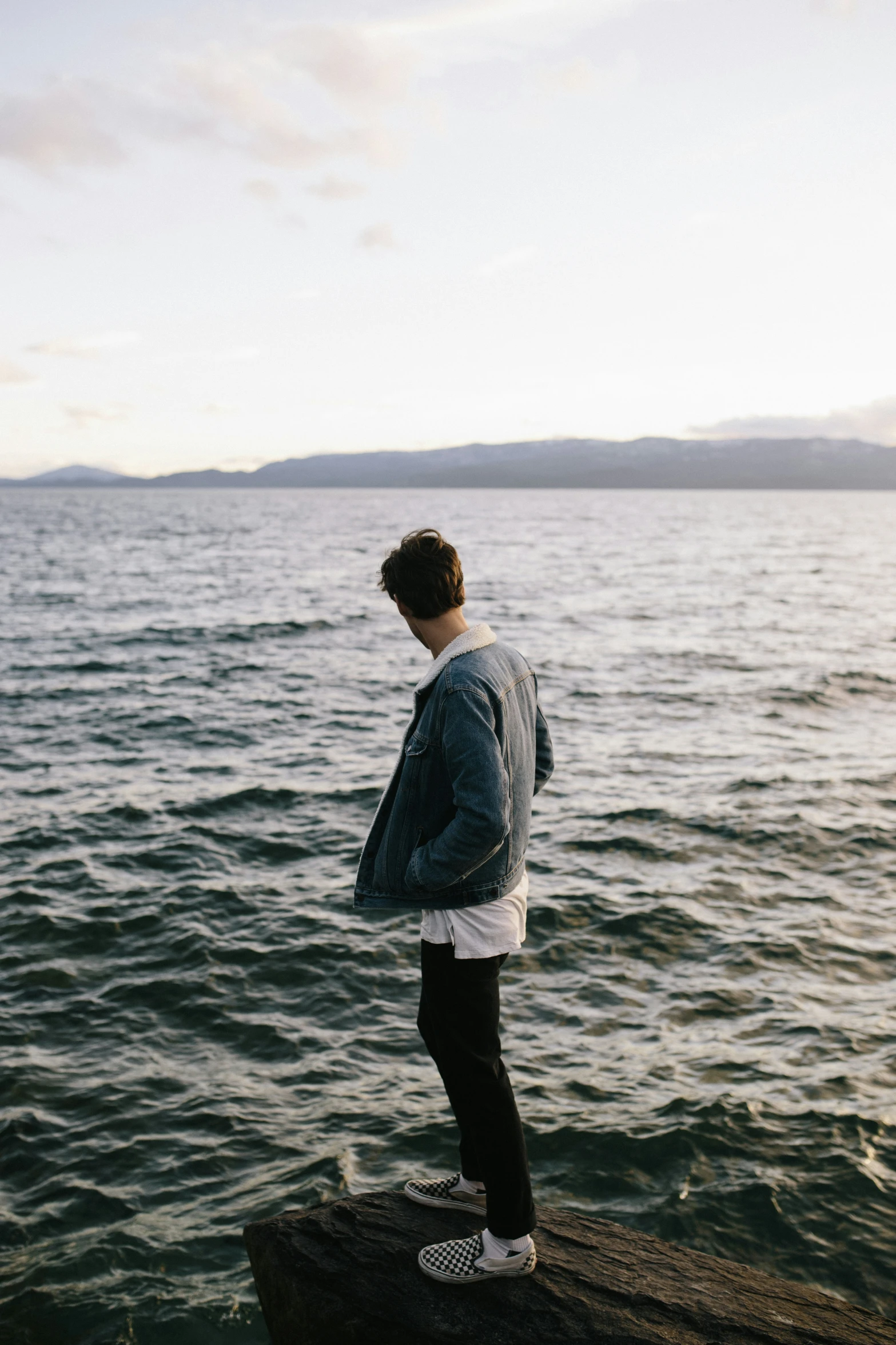 there is a man standing on the rocks by the water