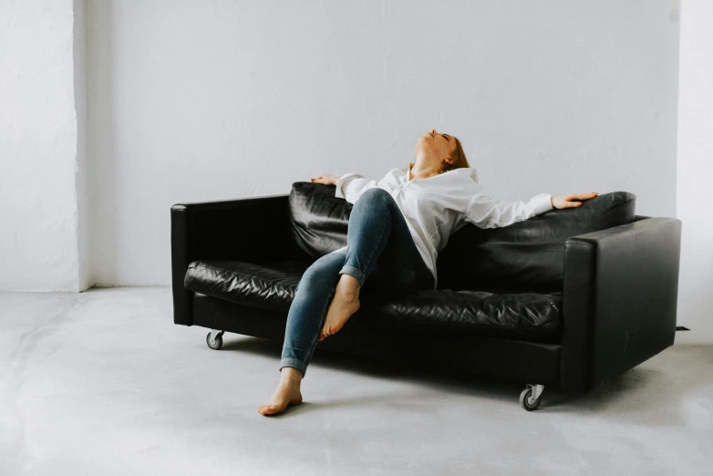 a woman sitting on a black couch with her eyes closed