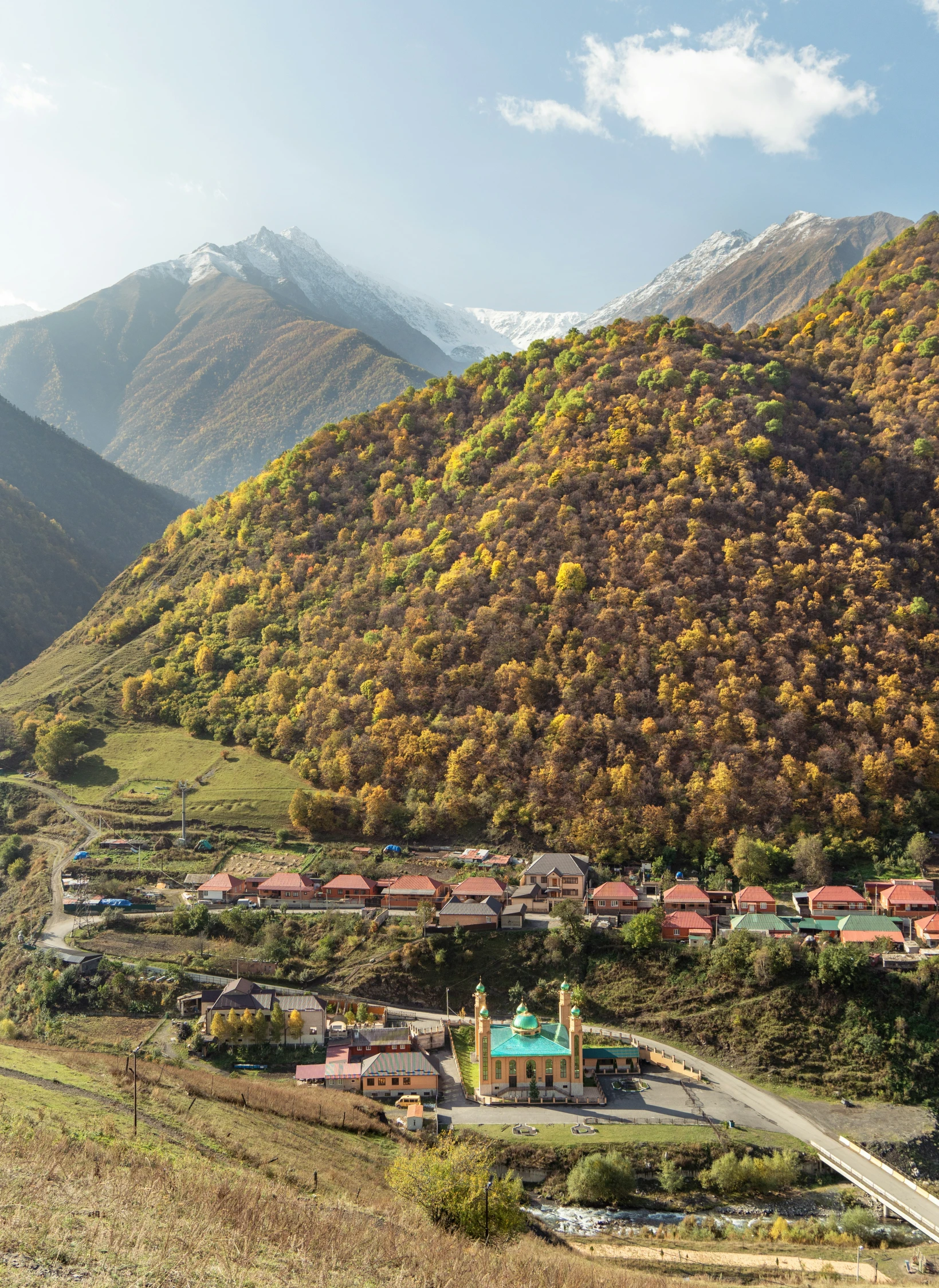 a street in front of some mountains with a church in the middle